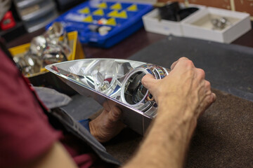 Car headlight in repair close-up. The car mechanic installs the lens in the headlight housing. The concept of a car service.Installation of LED lenses in the headlight. LED lens.Restoration of optics. © Dmitry Presnyakov