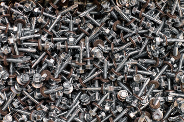 Bunch of galvanized self-drilling screws with washer and hexagonal head, hardware background
