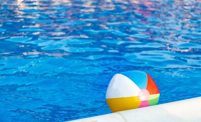The ball floats on the water surface in the pool under the summer sun