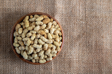Bowl full of dried mulberry on a fabric background
