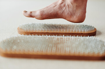 Woman try standing on Wooden Sadhu board with nails, yoga desk for regular practice, relieves...