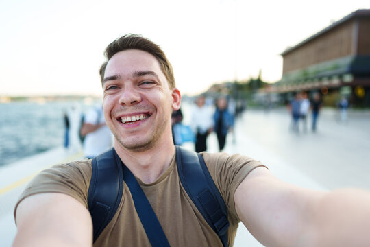 Young smiling man tourist taking a selfie on camera