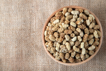Bowl full of dried mulberry on a fabric background
