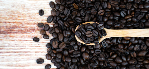 Roasted coffee beans in a wooden spoon. Copy space. Banner. Top view. Selective focus.