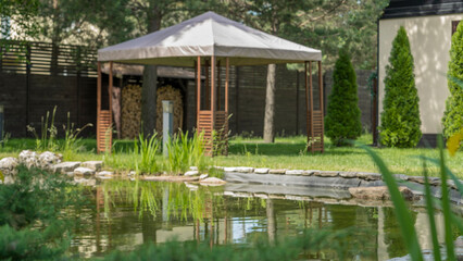 Beautiful landscaping with pond, plants and gazebo. Backyard garden landscaping. Landscape design.