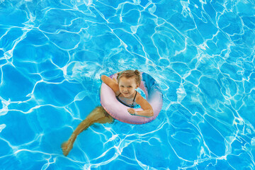  vacation in summer by the sea -  Child in swimming pool on ring toy. Kids swim.