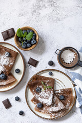 Celebrating Pancake day, healthy breakfast. Delicious homemade chocolate crepes with blueberries on a stone countertop. View from above. Copy space.