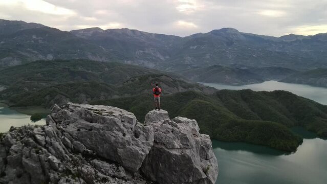 A man standing on the edge of the Albanian mountains with lake Bovilla in the background.