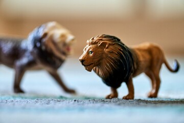 Closeup shot of a lion toy on the carpet with another on in the blurred background