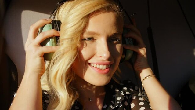 Young blonde girl puts on headphones sits in the cabin of a helicopter to fly a helicopter..