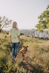 Woman standing in nature, next to her pit bull dog, looking at the city.