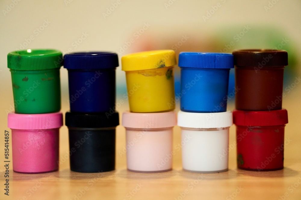 Poster closeup shot of a multicolored set of watercolors containers on a table with blurred background