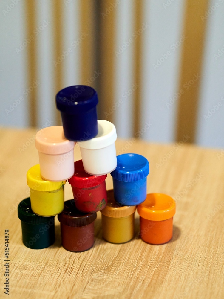 Poster closeup shot of a multicolored set of watercolors containers on a table with blurred background