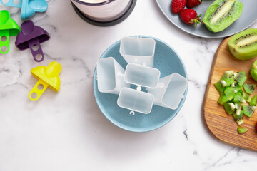 Top view of kitchen table preparing homemade ice cream from yogurt, strawberries and kiwi. Everything for making ice cream in molds.