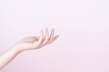 Woman hand presenting or showing open hand palm with copy space for product over pink background. Close up.