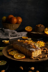Fototapeta na wymiar orange cake pudding with almonds and whole and sliced natural oranges and orange juice on a dark table