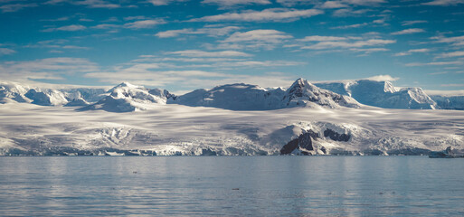 Fototapeta na wymiar Antarctica mountains and sea. Clouds and blue sky