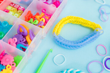 Closeup of making decorative bracelet with elastic bands on blue backround. Loom bracelets