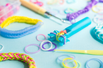 Closeup of making decorative bracelet with elastic bands on blue backround. Loom bracelets