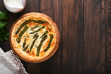 Quiche. Homemade asparagus pie or quiche with cheese and spinach on old dark wooden table background. Top view.