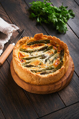 Quiche. Homemade asparagus pie or quiche with cheese and spinach on old dark wooden table background. Top view.