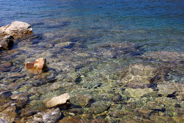 Transparent sea surface with stones on a bottom. Turquoise water for background