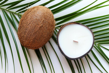 Fototapeta na wymiar original handmade soy wax candle in coconut, palm branch and 