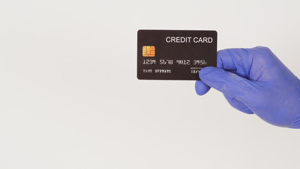 A black credit card in hand and wear violet or purple latex glove isolated on white background.