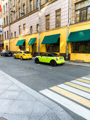 Obraz premium Colorful cars parked near a yellow wall on a city street.