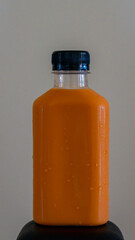 Thai tea bottle, black lid, placed on a black box creamy white background