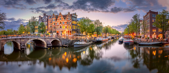 Amsterdam. Panoramic view of the downtown of Amsterdam.  A blue evening time and the serene reflection of lights in the water. Europe, Netherlands, Holland, Amsterdam.