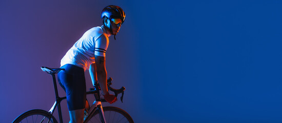 One male cyclist riding bicycle wearing cycling shorts and protective helmet isolated on dark blue background in neon. Concept of sport, speed, energy - obrazy, fototapety, plakaty