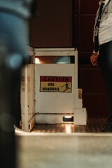 Vertical shot of a man standing next to a caution sign of stairs warning to use handrail