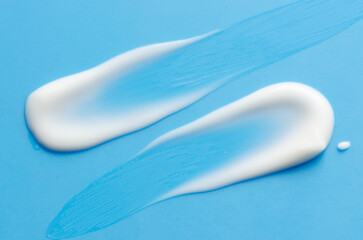 A sample of white moisturizer on a blue background. Cosmetic product for the skin.