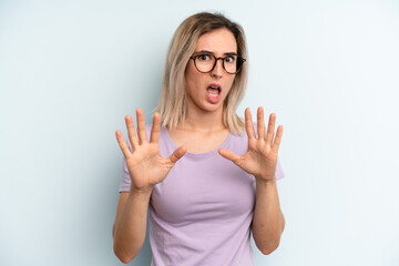 young adult pretty woman feeling terrified, backing off and screaming in horror and panic, reacting...