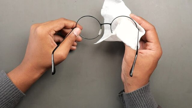 mean cleaning eyeglass with tissue top view 