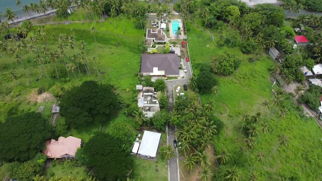 Aerial slow movement around Apo Vista beach surrounded by buildings and green trees