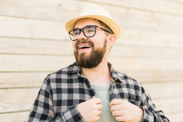Laughing attractive man wearing hat over wooden background - emotion and vacation travel holidays concept