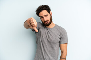 young adult bearded man feeling cross, angry, annoyed, disappointed or displeased, showing thumbs...
