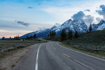 Scenic Road surrounded by Mountains and Trees in American Landscape. Spring Season. Grand Teton National Park. Wyoming, United States. Nature Background.