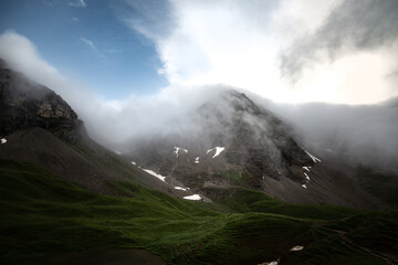 Mountain peaks in the fog of an upcoming storm with a green valley underneath in the alps of the Allgäu in Germany