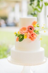 Vertical shot of a white wedding cake decorated with flowers isolated on a blurred background