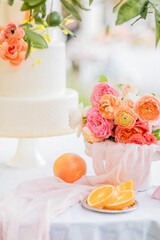 Vertical shot of an outdoor wedding table with flowers, oranges, and a cake in the background