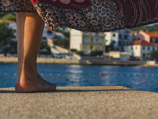 Blurred sunny summer background Croatia with feminine feet near the water.