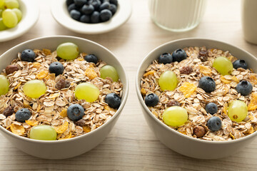 Zwei Schalen mit Müsli und frischen Weintrauben und Heidelbeeren