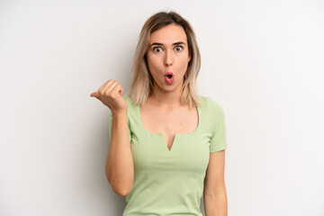 young adult blonde woman looking astonished in disbelief, pointing at object on the side and saying...