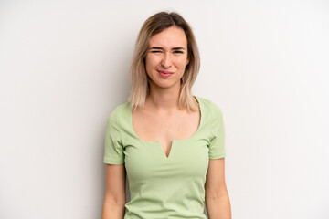 young adult blonde woman looking puzzled and confused, biting lip with a nervous gesture, not...
