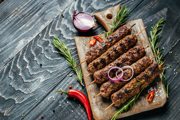 Shish kebab on a stick, from ground beef meat on the black background. chopping board. Lula kebab,...