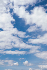 Blurred image of a blue sky with fluffy white clouds.