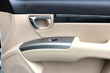 Passenger door handle with windows controls and adjustments in light leather interior. Window switches. Passenger door trim.